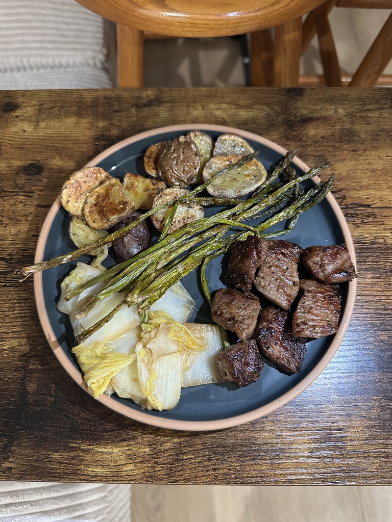Steak bites with skinny asparagus, kind of roasted potatoes, and flavorful cabbage